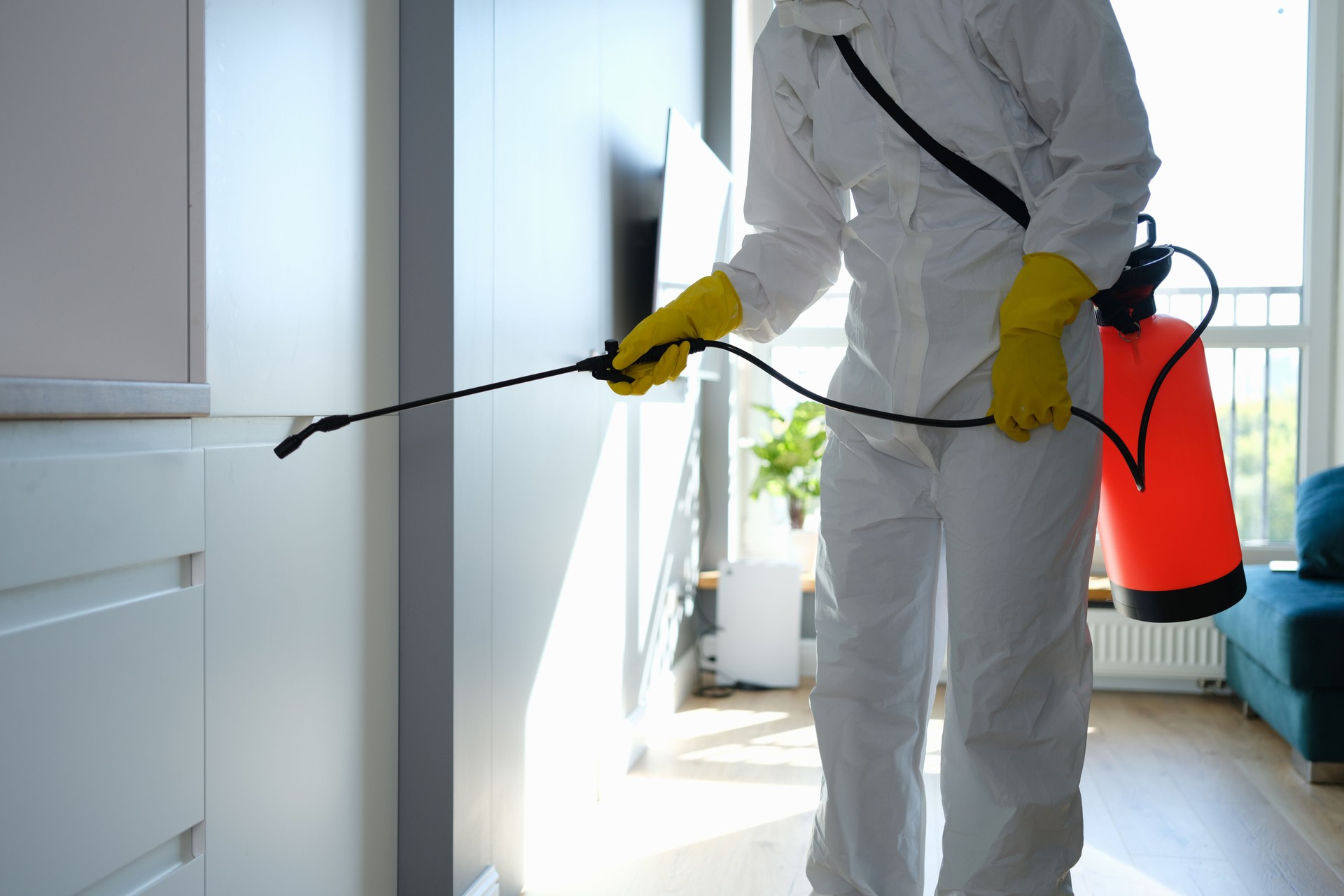 Technicien en combinaison de protection réalisant une opération de dératisation dans un appartement à Paris 12